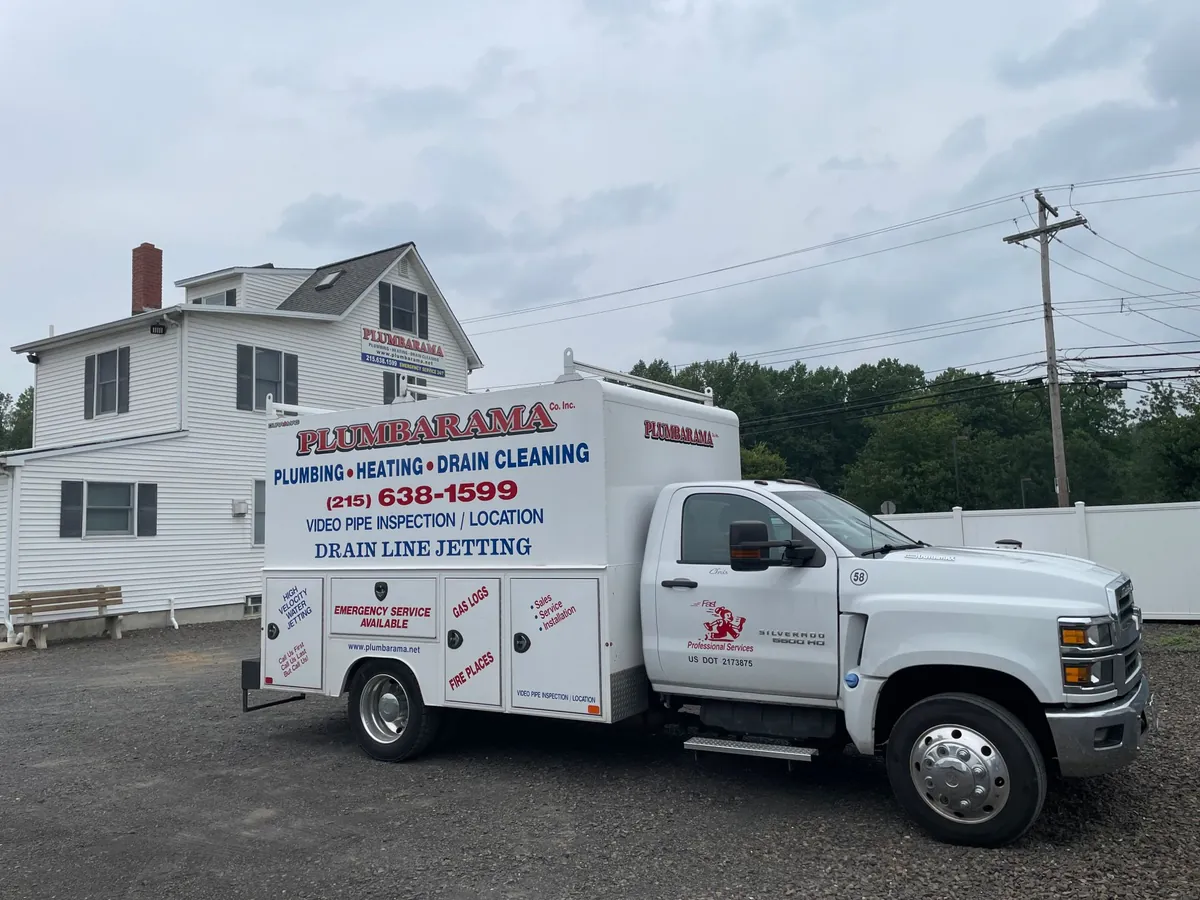 Plumbarama truck lettered for plumbing, heating, drain cleaning and drain line jetting, parked outside the company shop